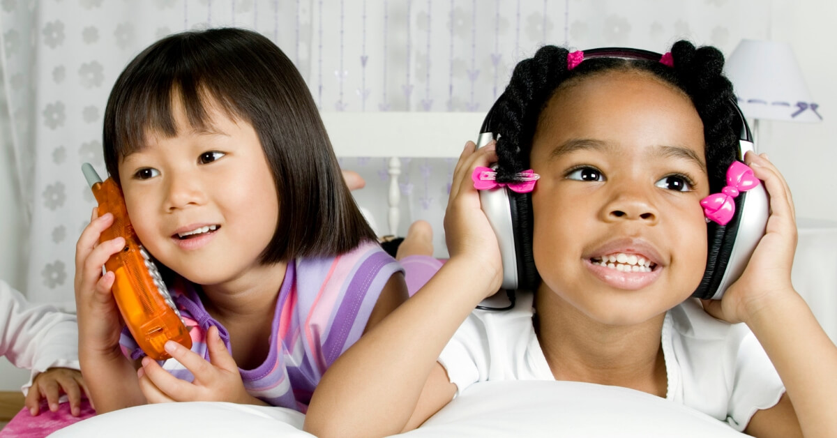 2 young girls using a play phone and headphones