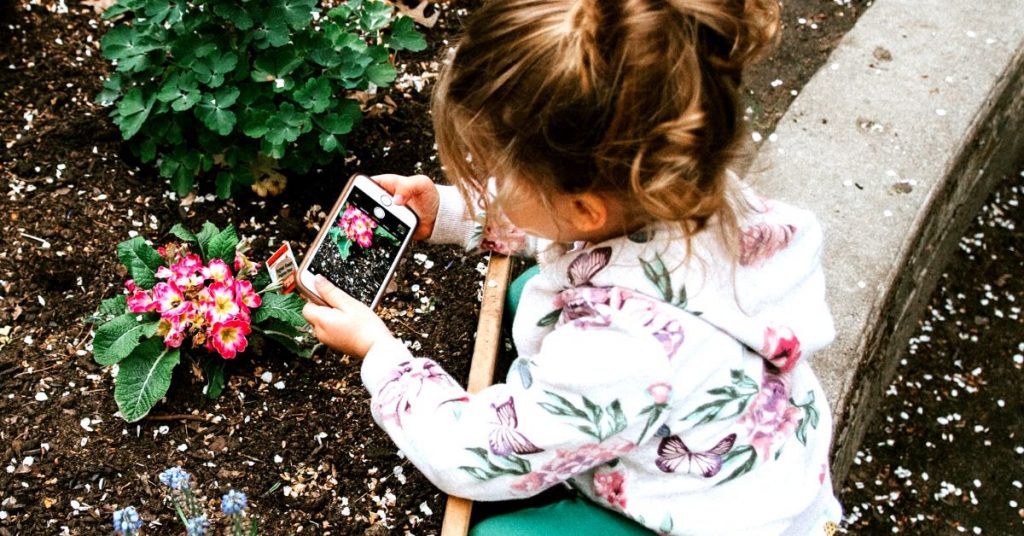 Girl taking photo of plant on iphone (1)