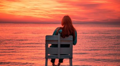 Woman-sitting-on-beach-at-sunrise.jpg